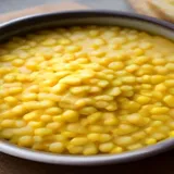 Tigela de creme de milho cremoso com grãos inteiros visíveis, salpicado de cheiro-verde
