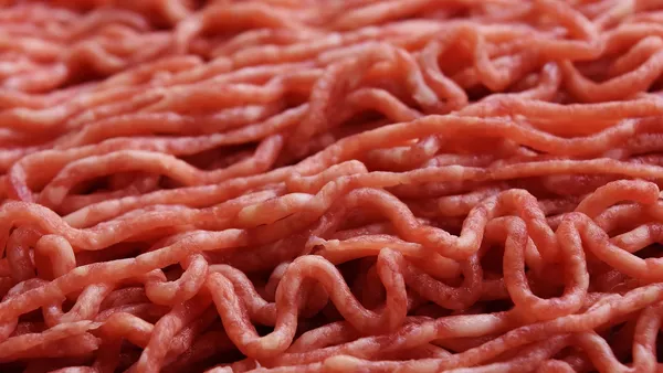 Gomos de linguiça artesanal dourados na grelha da churrasqueira ao lado de uma frigideira de ferro com farofa amarela