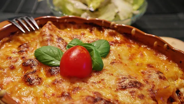 Pedaço de lasanha à bolonhesa servido num prato, camadas bem definidas de massa, molho de carne e queijo derretido