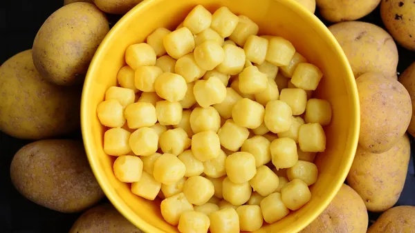 Nhoques de batata claros e macios sobre uma colher, com marcas de garfo, ao lado de molho de tomate