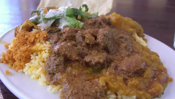 Tigela de curry de lentilha vermelho-alaranjado encorpado com coentro fresco e arroz branco ao lado