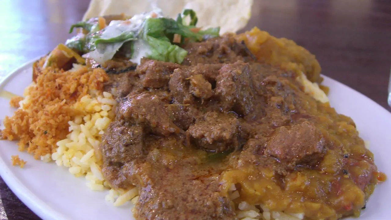 Tigela de curry de lentilha vermelho-alaranjado encorpado com coentro fresco e arroz branco ao lado