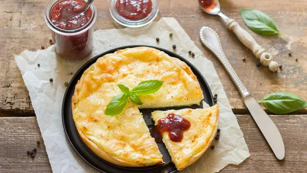 Fatia de quiche de alho-poró com base dourada e crocante, recheio cremoso amarelo claro com anéis de alho-poró visíveis